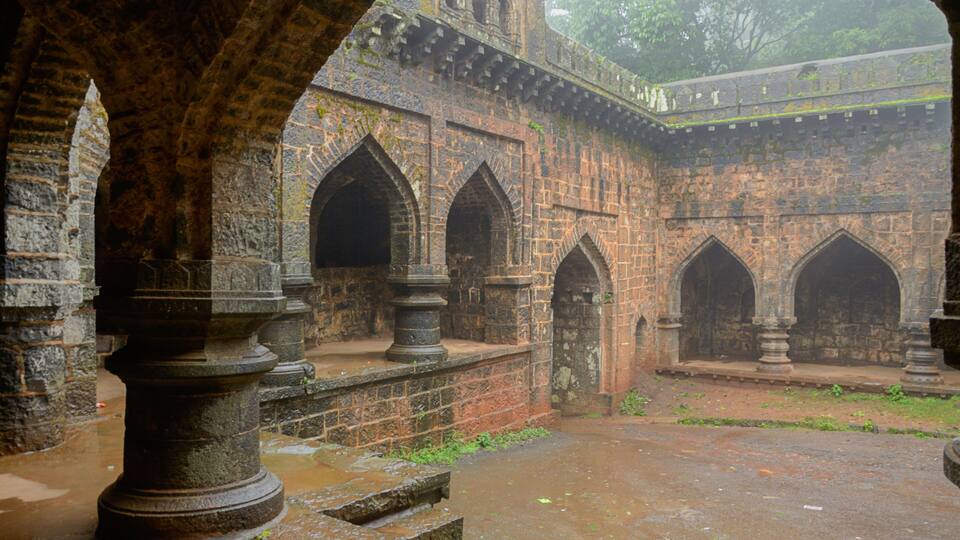 An ancient stone structure with arched doorways and a covered walkway.