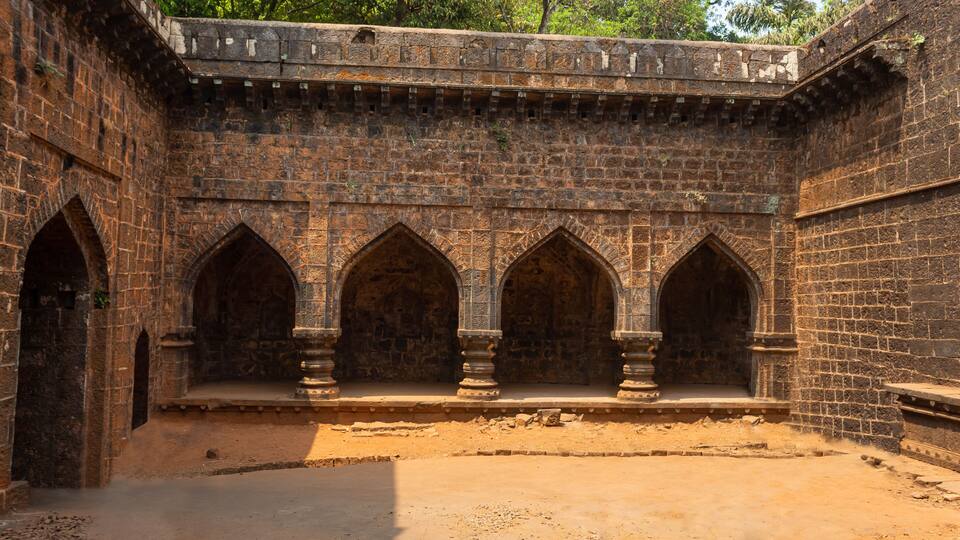 A stone building with arched windows and a brick wall.