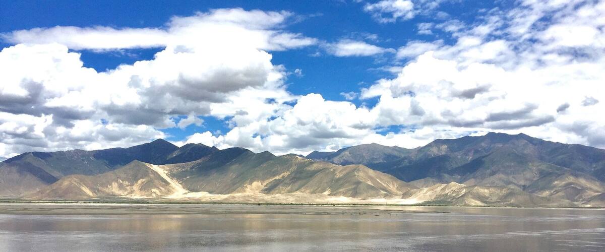 A mountain range with a reflective body of water in the foreground.