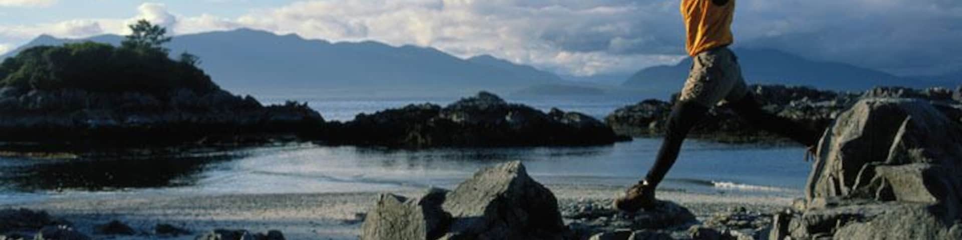 Canada, British Columbia, Barkley Sound, woman jumping on rocks