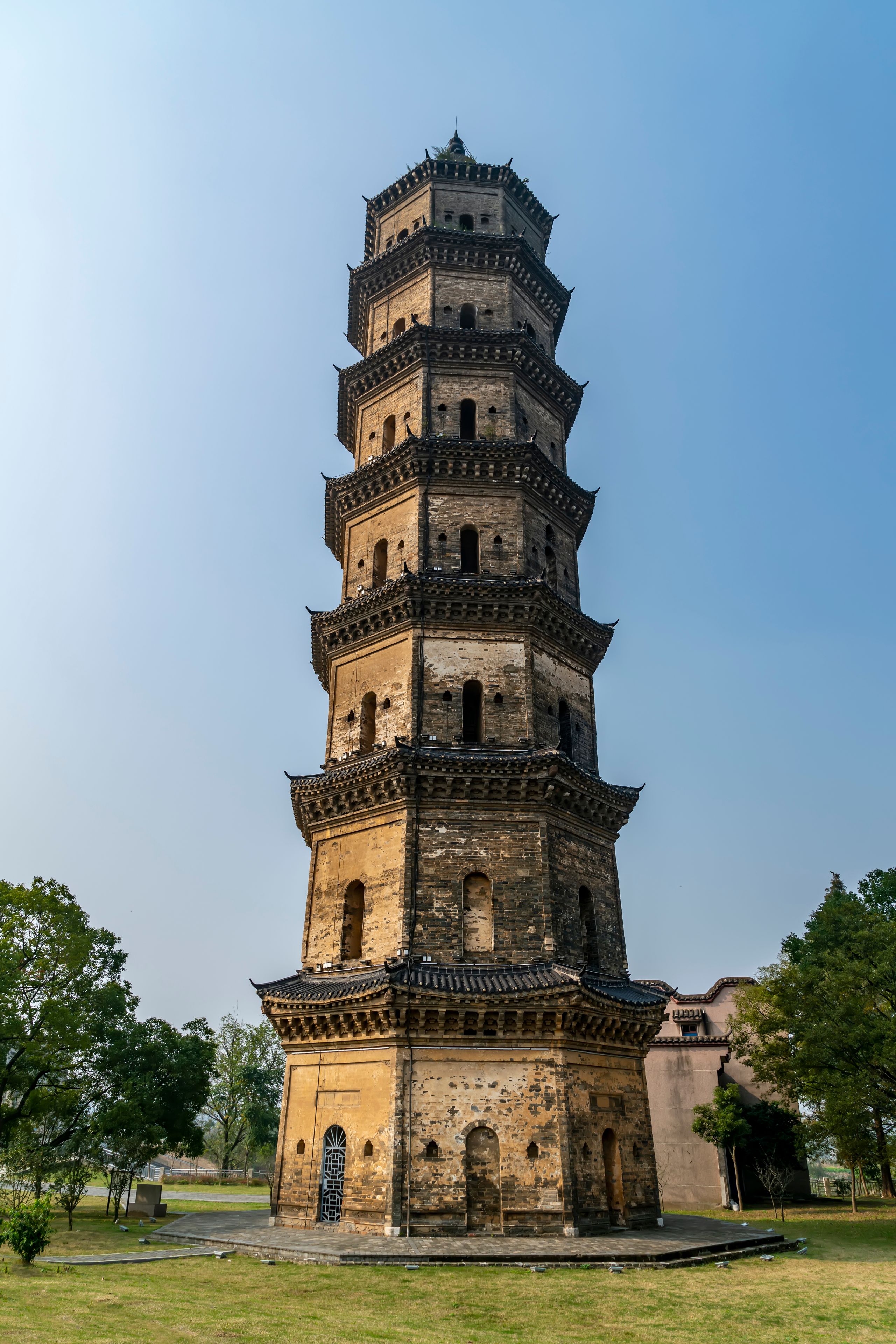 Un pagodas de varios niveles con arquitectura tradicional, rodeado de césped y árboles.