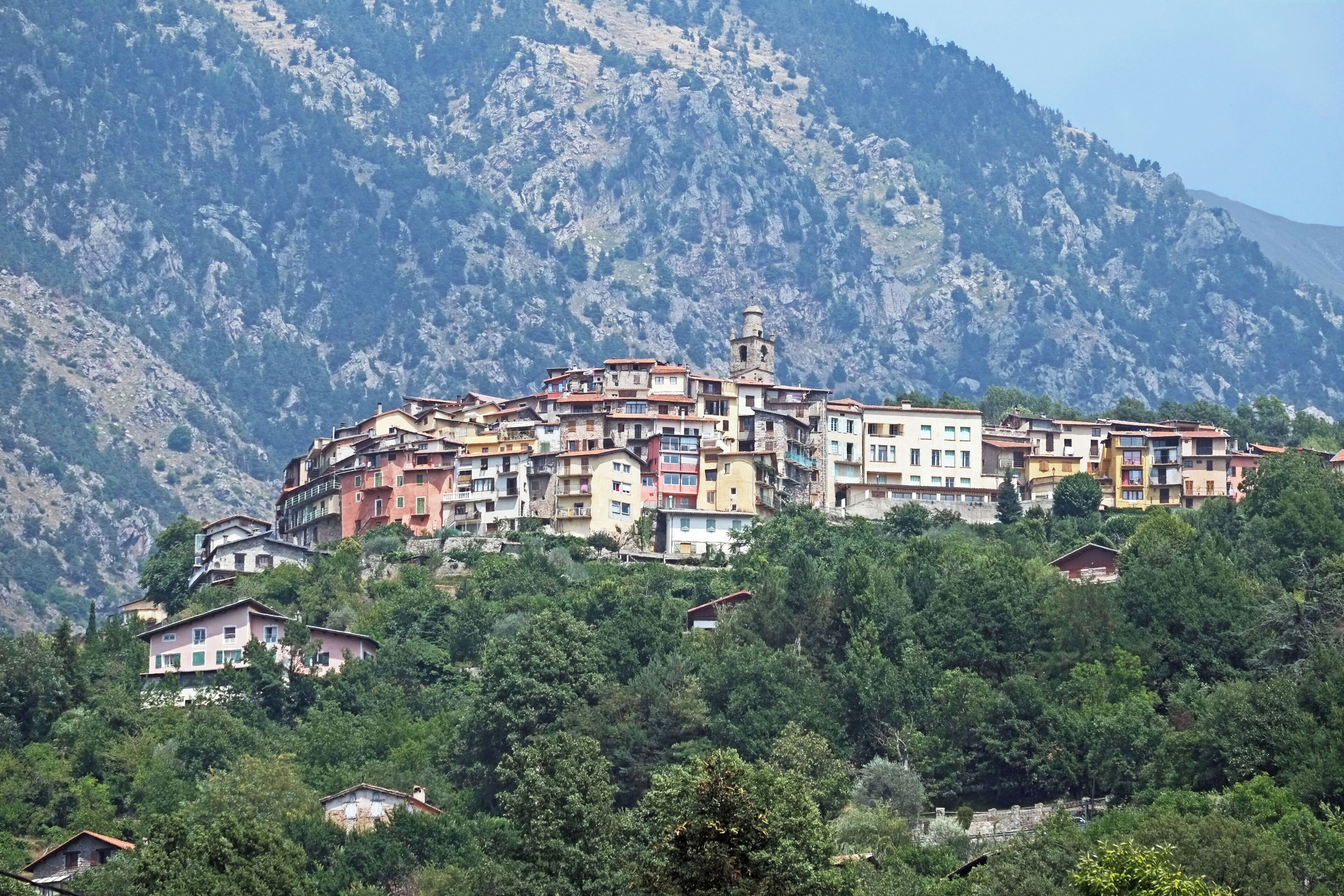 A hillside village with colorful buildings, a prominent tower, and lush greenery.