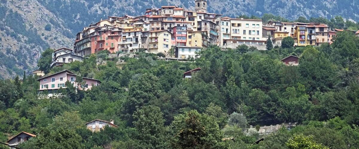 A hillside village with colorful buildings, a prominent tower, and lush greenery.