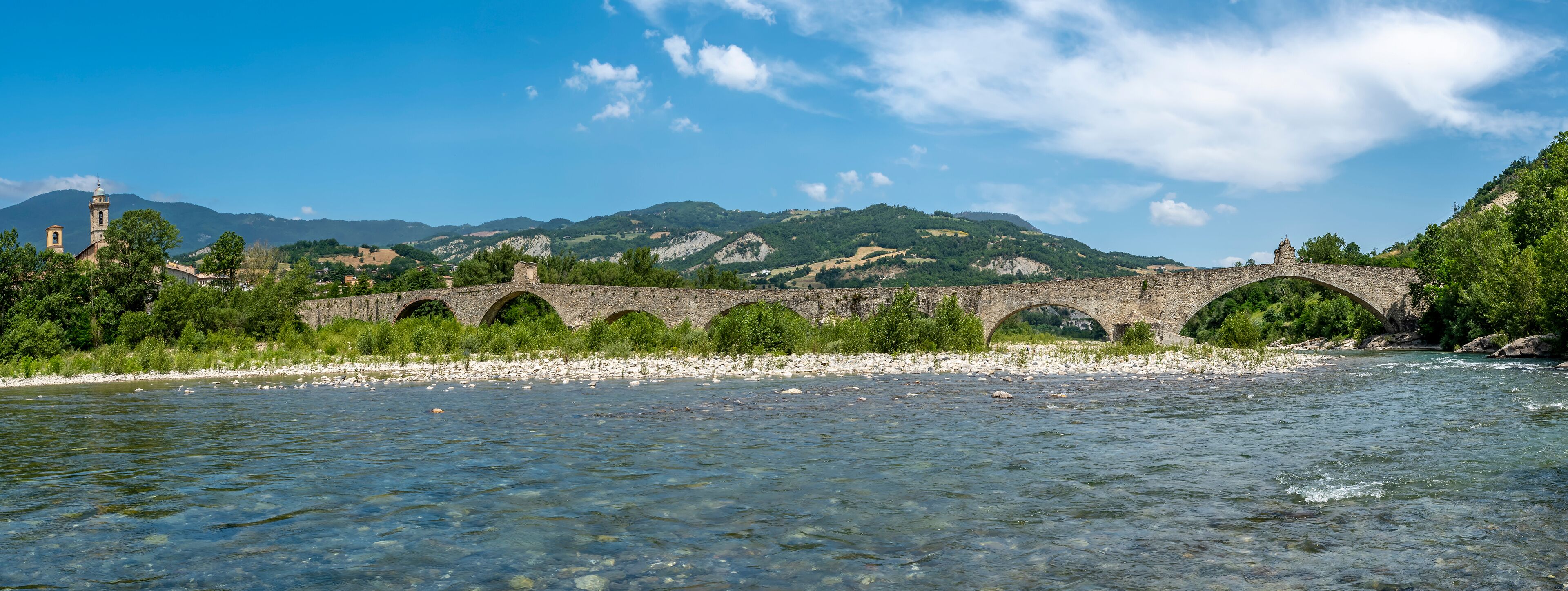 The Trebbia river flows under the ancient Gobbo bridge in Bobbio, Italy