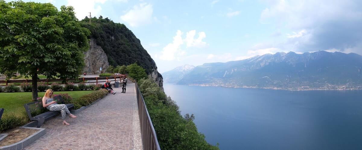 A scenic overlook with a view of a lake, mountains, and a distant city.