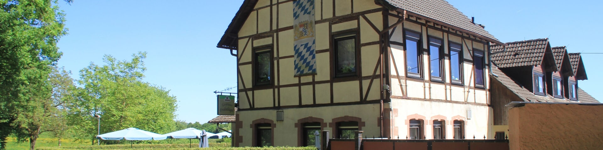 A traditional half-timbered house with a tiled roof, a gated entrance, and a clear blue sky.