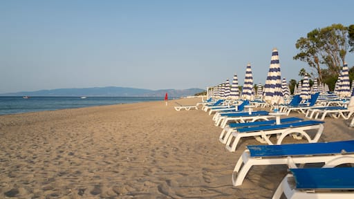 Blue and white umbrella and beach chairs at the beach in front of blue sea and blue sky. Calabria, Simeri Mare, Italy.
