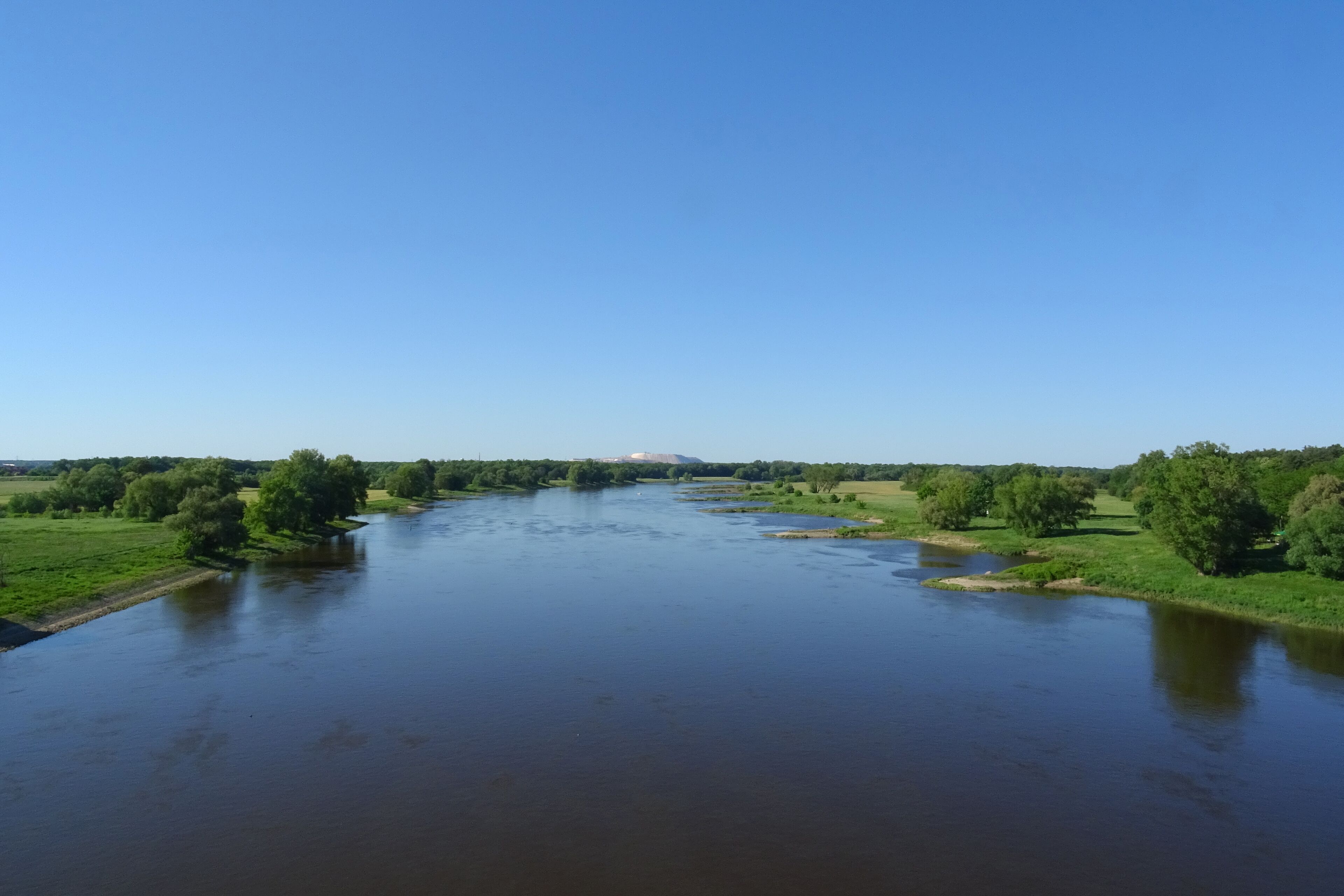 A river flowing through a green landscape with trees and open fields.