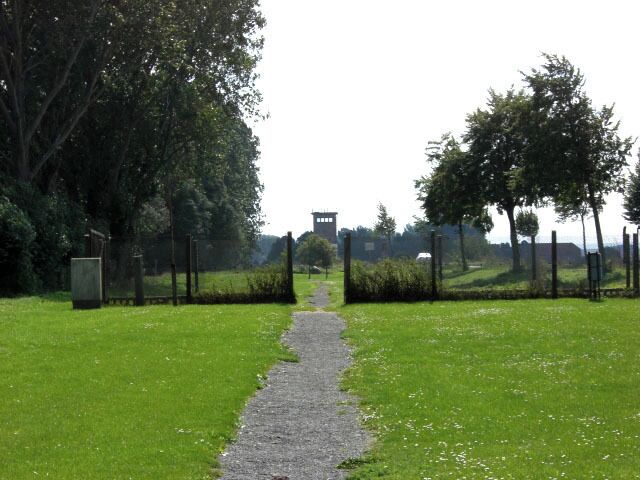 A gravel path leading to a building surrounded by trees and grass.