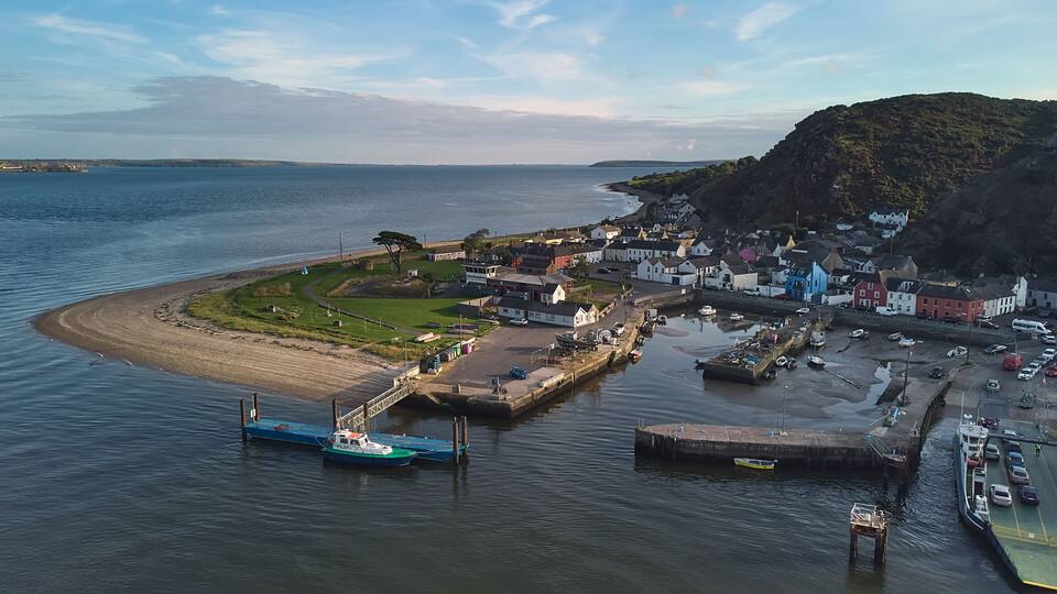 A coastal town with a harbor, boats, and a small island with houses.