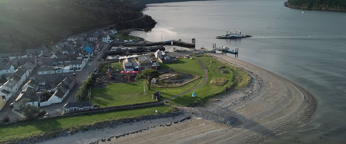An aerial view of a coastal town with a harbor, a lighthouse, and a large body of water.