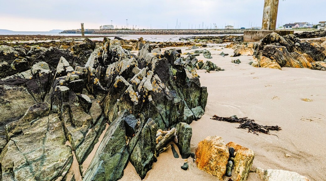 The rocky beach with concrete towers at Kilmore Quay, a fishing village in County Wexford, Ireland