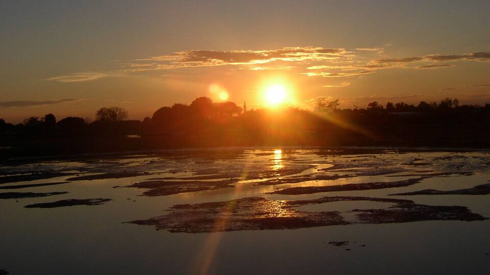 A sunset over a frozen lake with reflections of the sun.