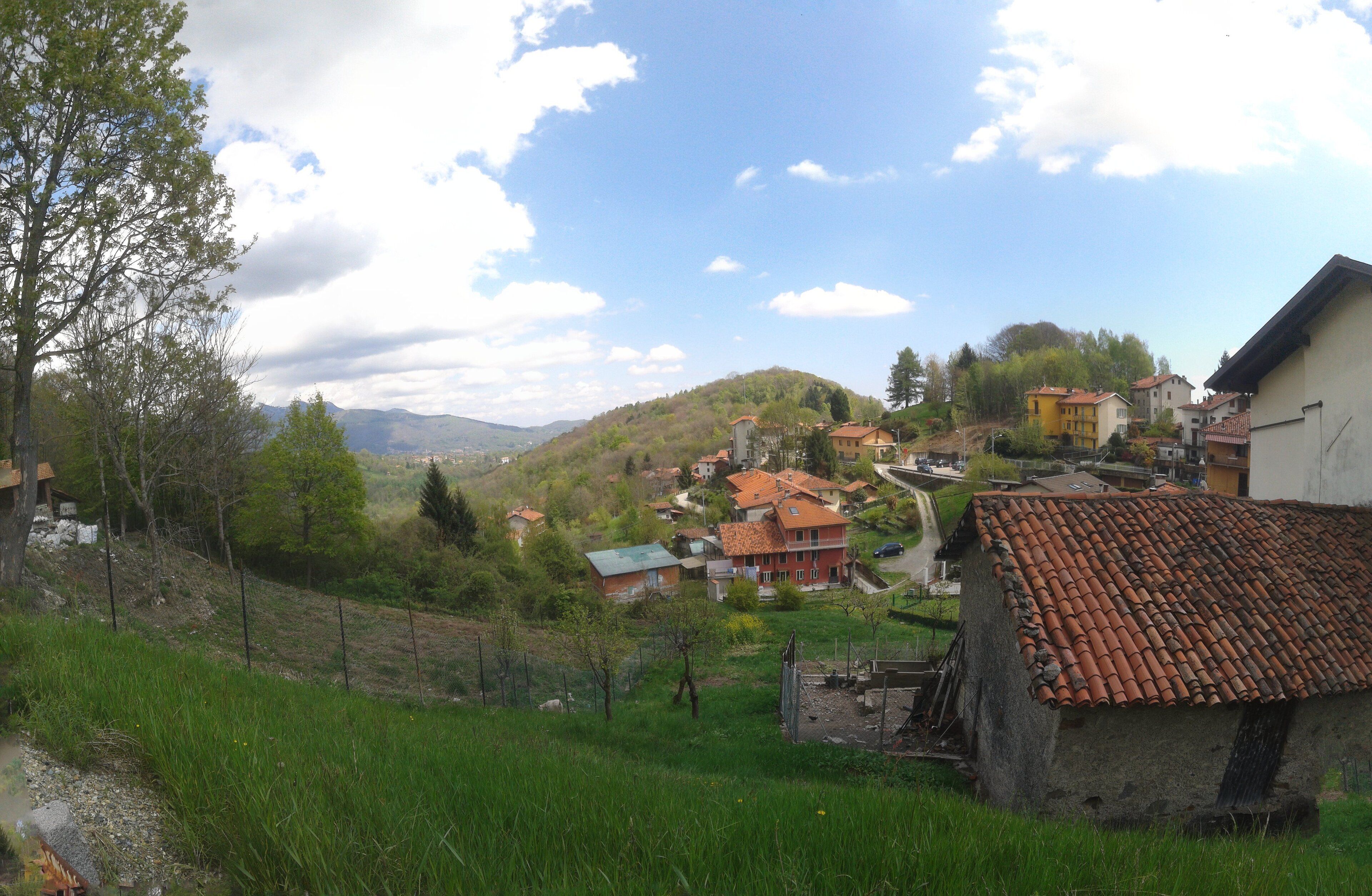 A hillside village with terracotta-roofed houses, a stone building, and a grassy foreground.