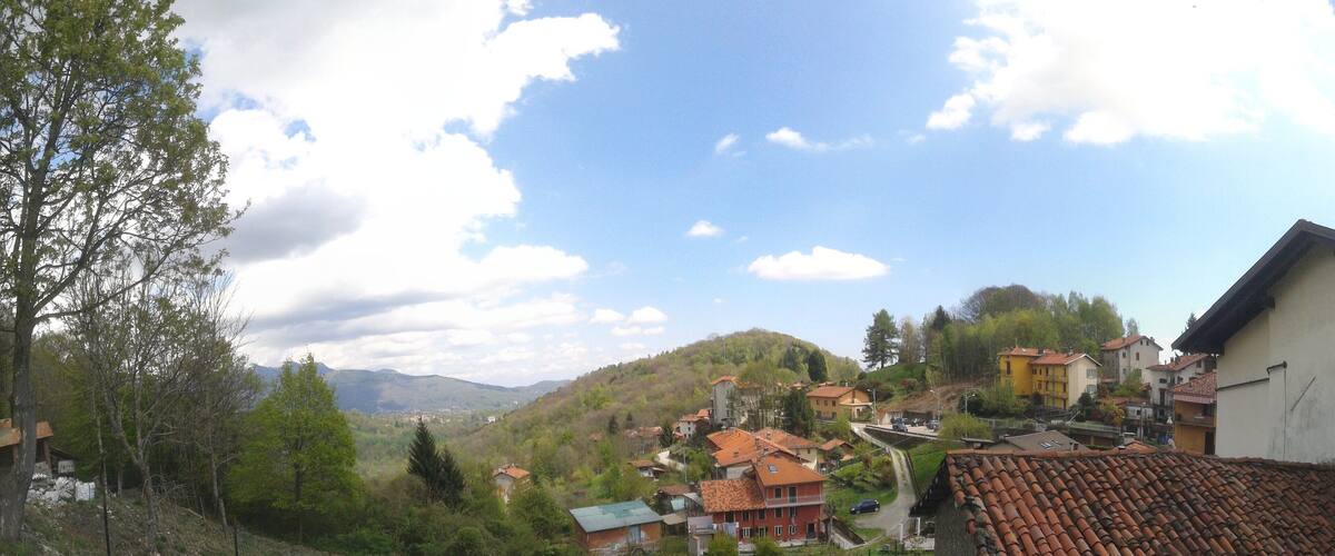 A hillside village with terracotta-roofed houses, a stone building, and a grassy foreground.