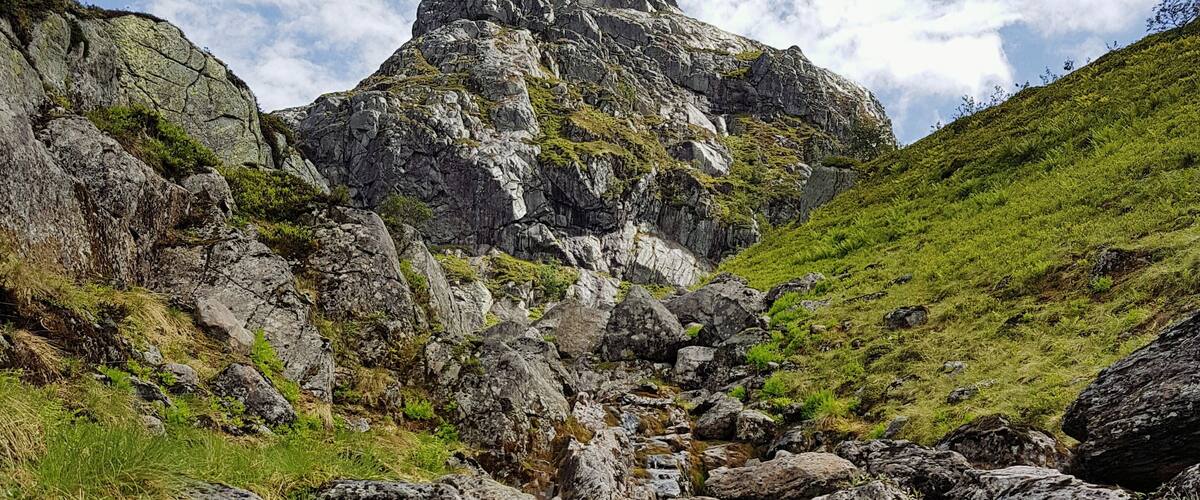 A rocky stream bed with large boulders and a mountain in the background.