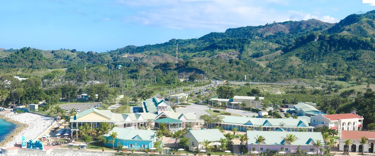 A coastal town with buildings, a beach, and a mountainous backdrop.