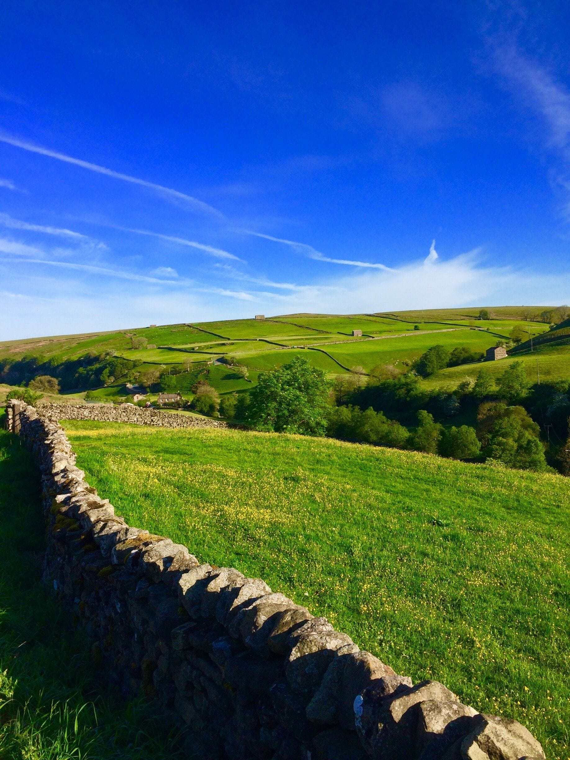 A stone wall, rolling hills, and a clear blue sky.