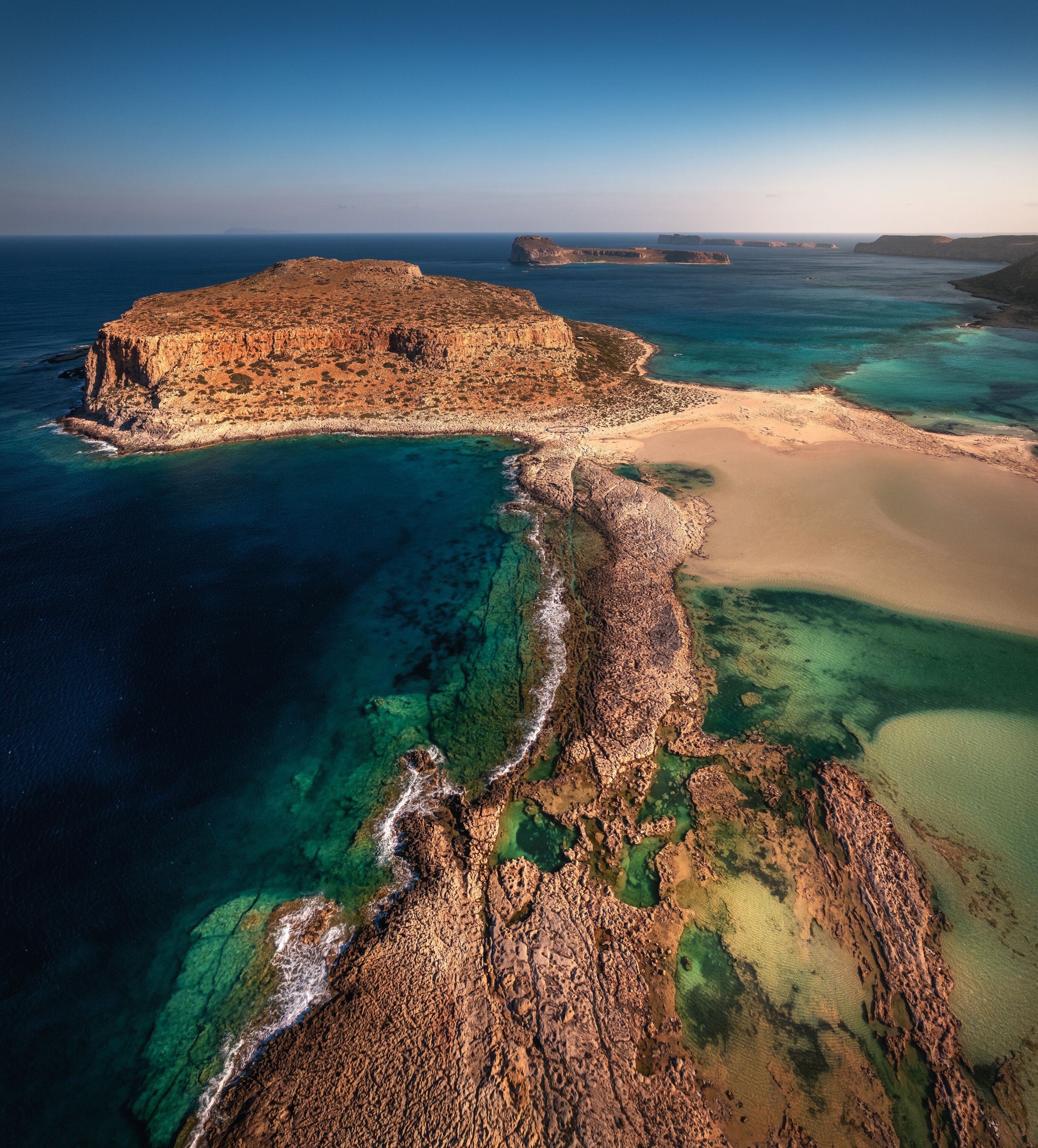 Majestic Morning at Balos, Crete: Serene turquoise waters caress the white sandy beach, embraced by dramatic cliffs under the golden morning sunlight