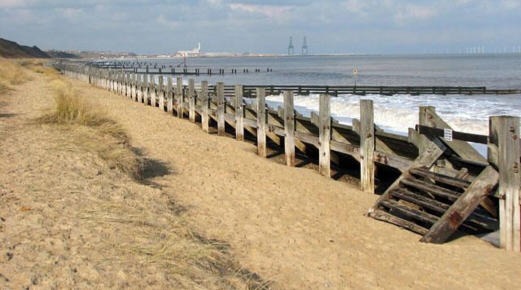 Groynes and revetment on the beach below Hopton-on-Sea. The Norfolk coastline is almost 100 miles long and extends from Hopton, just south of Great Yarmouth, northwards past the seaside resorts of Winterton, Happisburgh, Mundesley, Cromer, Sheringham and Holkham before it merges into Lincolnshire at King's Lynn. After the devastating floods in 1953, where 300 people lost their lives, the first sea defences were built along the coastline and at first the rate of erosion decreased. However, large portions of the revetments have been destroyed during the last 40 years, despite repairs, and beach and cliff erosion continue. The Shoreline Management Plan in its present format proposes no active intervention for a number of villages along the East Anglian coast, leaving them unprotected. One of these villages is Hopton, situated several miles south of Great Yarmouth, where the southern end of the Hopton to Corton seawall had to be closed due to storm damage, with the anticipation of a collapse of the structure > 1717919. A warning for walkers to take extra care has also been placed at the clifftop path > 1717876 where cliff falls on the path to Corton have occurred recently and more are expected > 1717883. Some blame the existence of the new outer harbour in Great Yarmouth for the loss of sand and beach area, and although some of the sand has since returned it is still at a low level. The privately owned East Port at Great Yarmouth, a multi-purpose facility integrating a new deep-water outer harbour, was opened in May 2007.