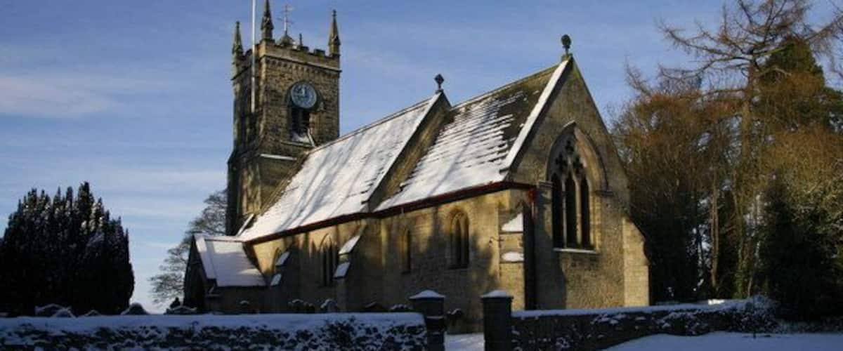 A church with a clock tower and snow-covered surroundings.