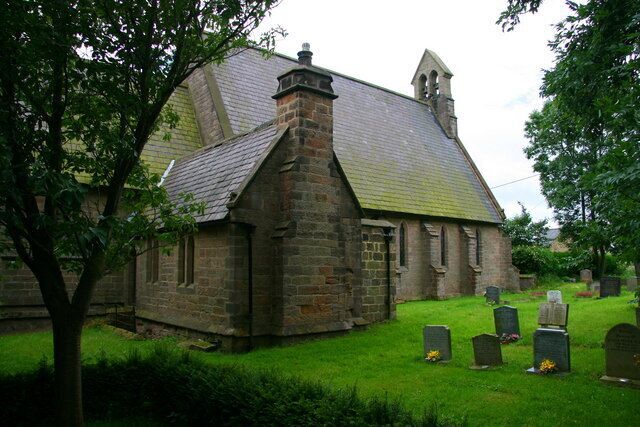 A stone church with a steep roof and a bell tower, surrounded by a cemetery with headstones.