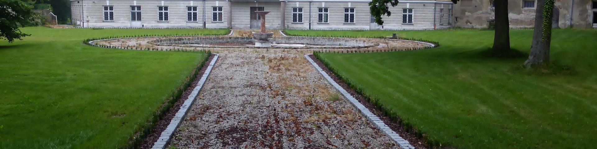 A building with a symmetrical facade, a central entrance, and a gravel pathway leading to it.