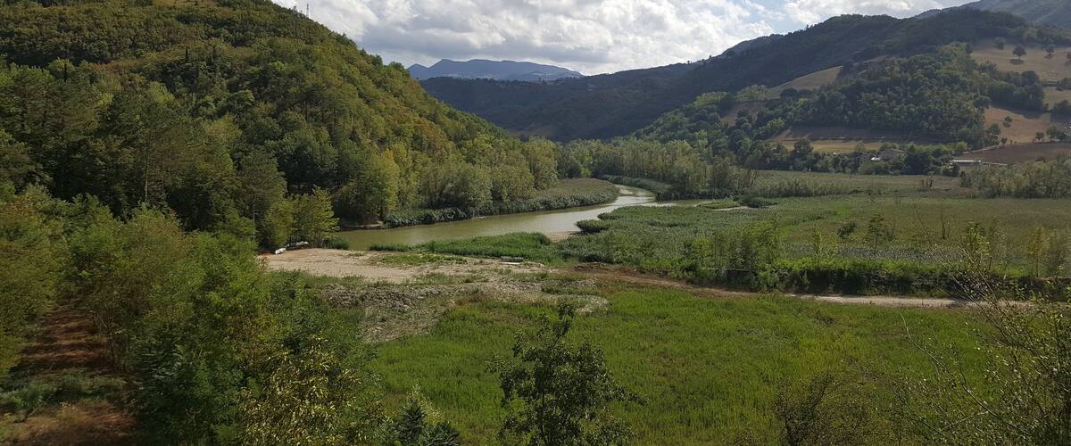 A river winding through a valley with dense forests and hills in the background.