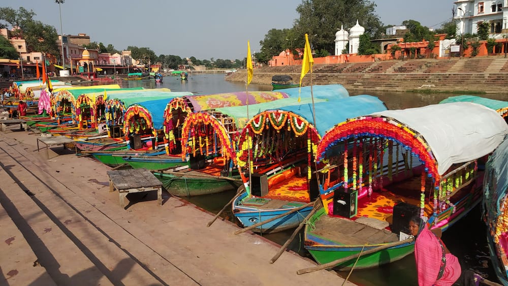 A row of colorful boats adorned with garlands, docked along a riverside.