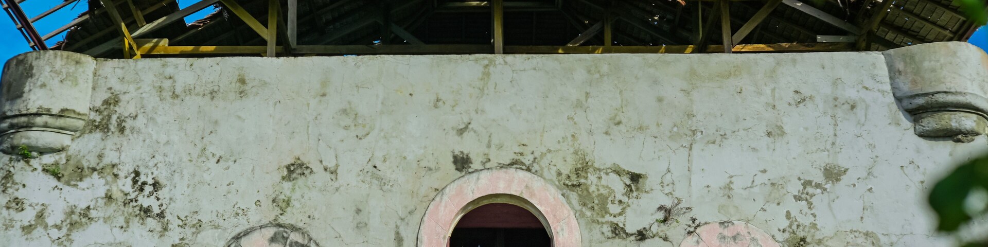 Um edifício desgastado pelo tempo, com janelas em arco e uma varanda.