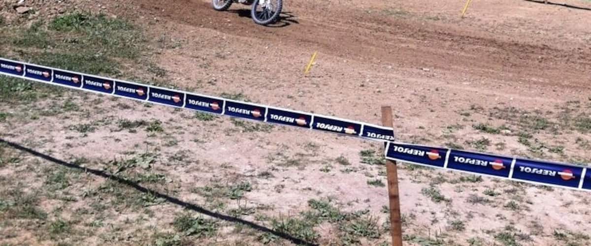 A motocross event with a rider on a dirt bike, spectators, and a hilly backdrop.