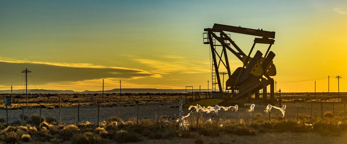 A large oil pumpjack in a desert landscape during sunset.