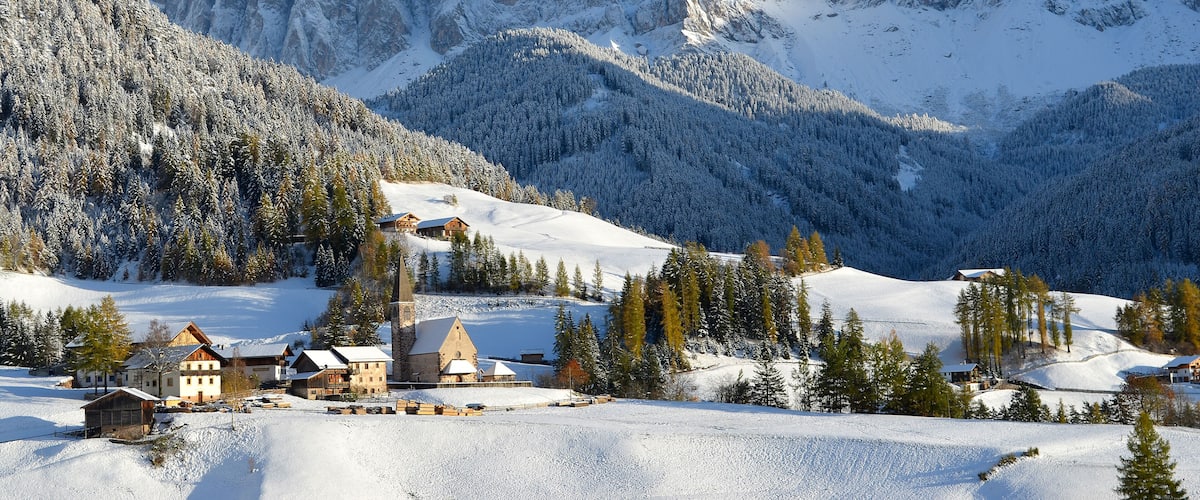 A snow-covered mountain range with a village at its base.