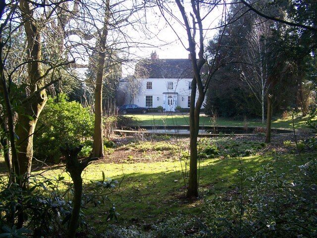 A white house surrounded by trees and a grassy area.
