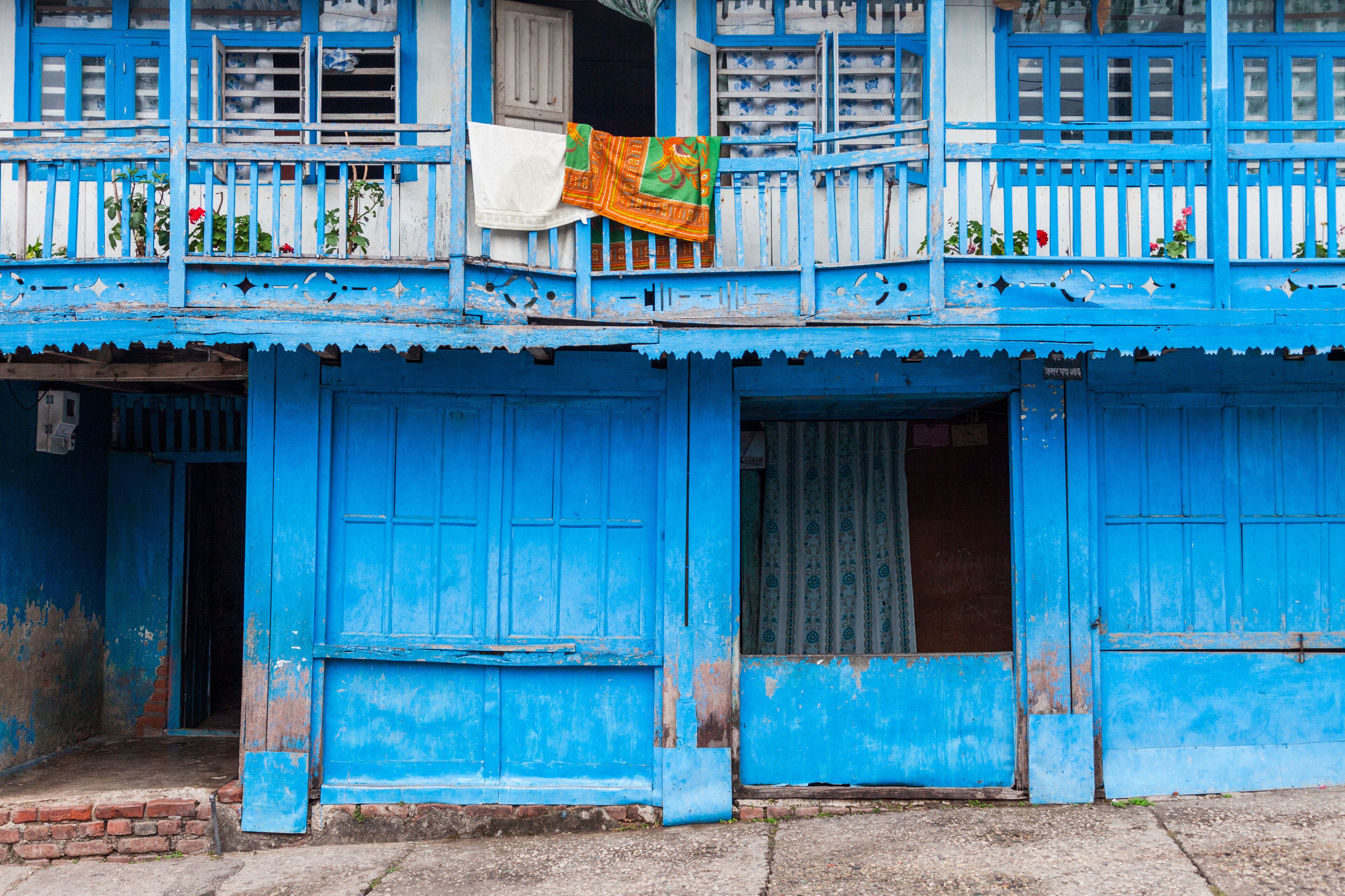 A blue building with a balcony and a hanging cloth.