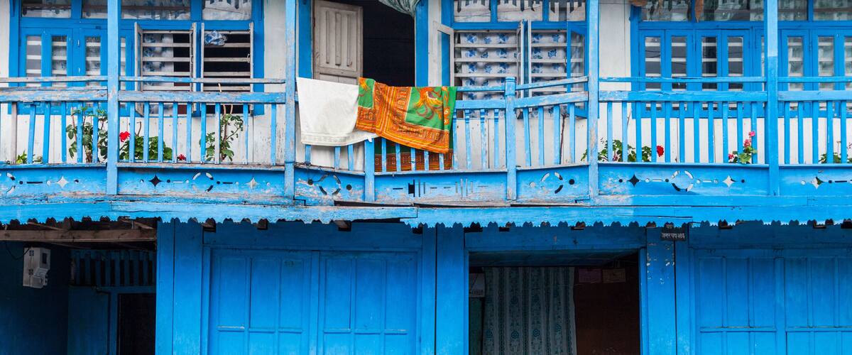 A blue building with a balcony and a hanging cloth.
