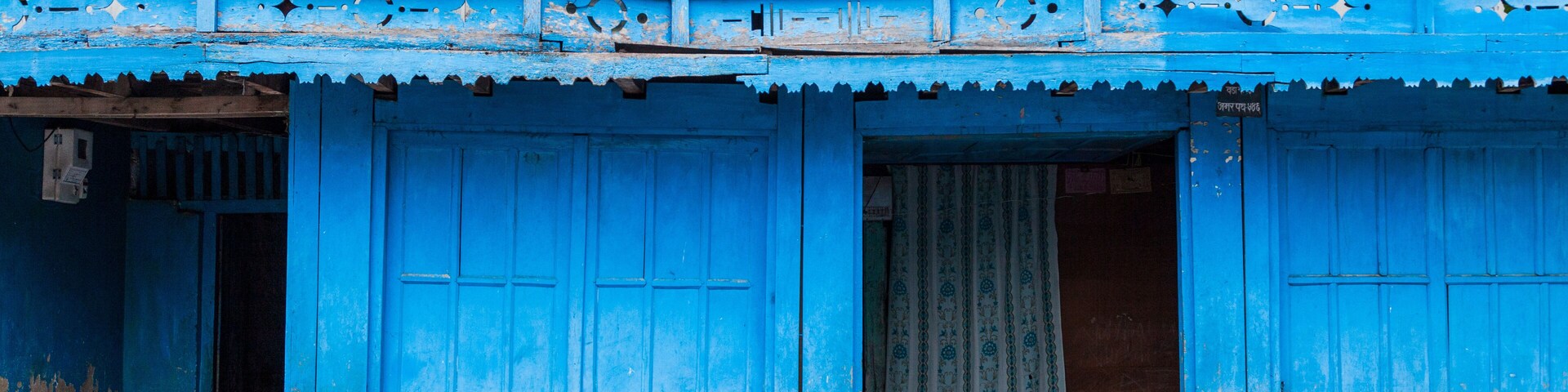A blue building with a balcony and a hanging cloth.
