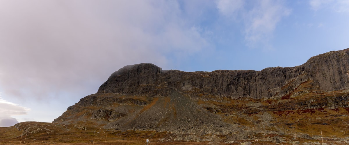 A rugged mountain landscape with a prominent rocky peak and sparse vegetation.