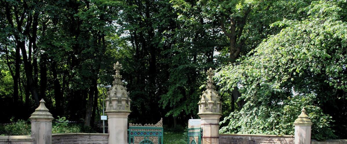 A gated entrance with ornate pillars and a decorative gate, surrounded by lush greenery.