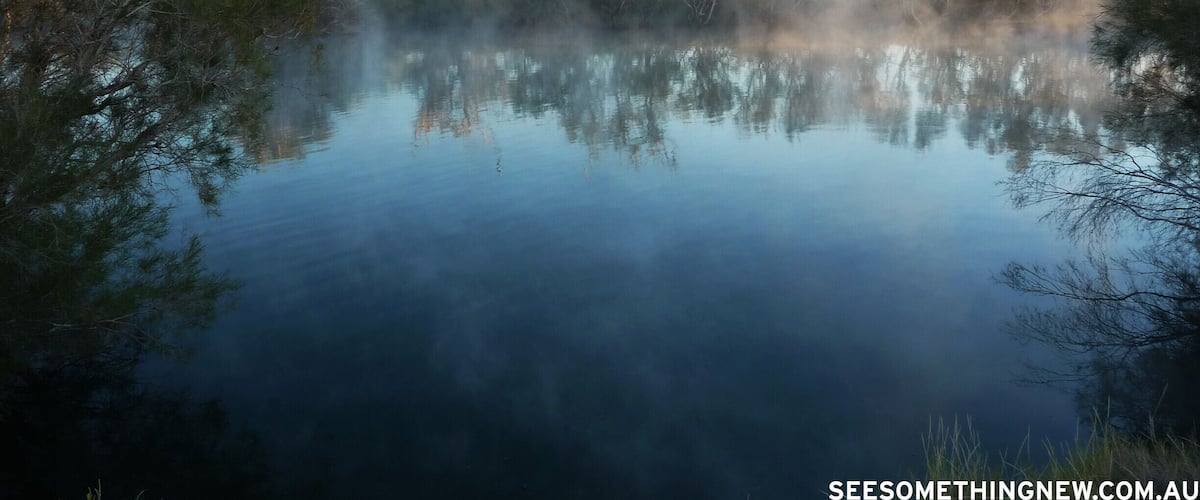 A calm lake with reflections of trees and a clear sky.