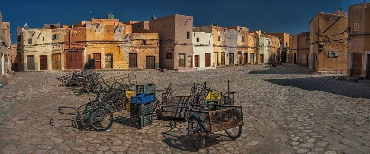 A cobblestone street in a historic town with old buildings and a cart with crates.