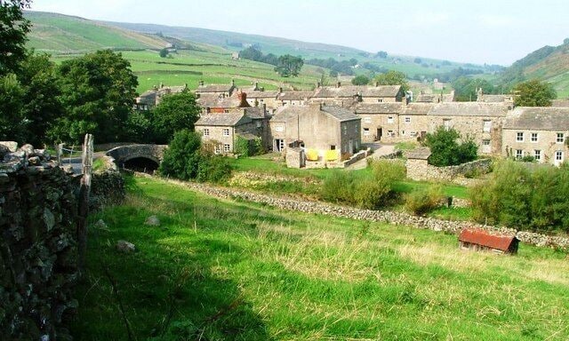 A rural village with stone houses, a stone wall, and a bridge.