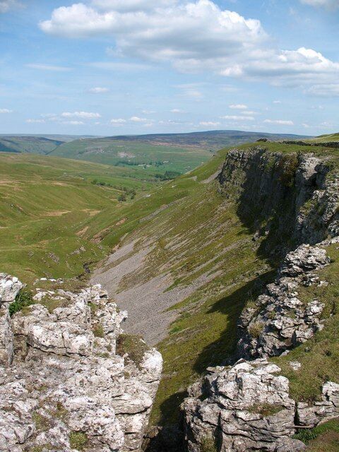 A rocky cliff edge with a valley below.