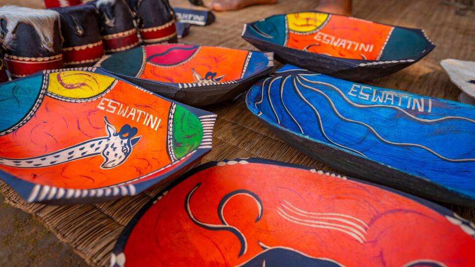A collection of colorful, hand-painted plates with various designs and the name 'ESWATINI' on them.
