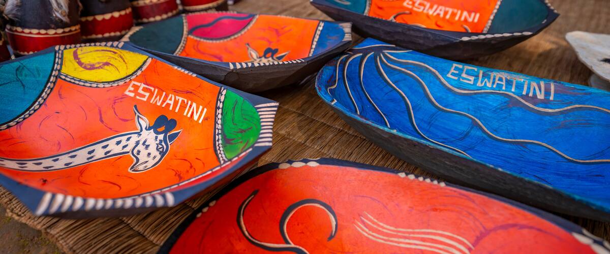 A collection of colorful, hand-painted plates with various designs and the name 'ESWATINI' on them.