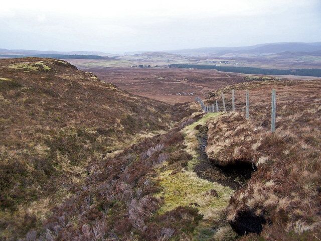 A hilly landscape with a narrow path and a fence.