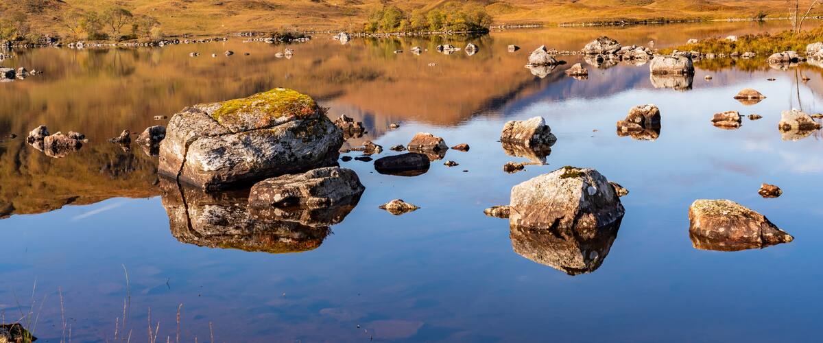A tranquil lake surrounded by mountains with clear reflections of the landscape.