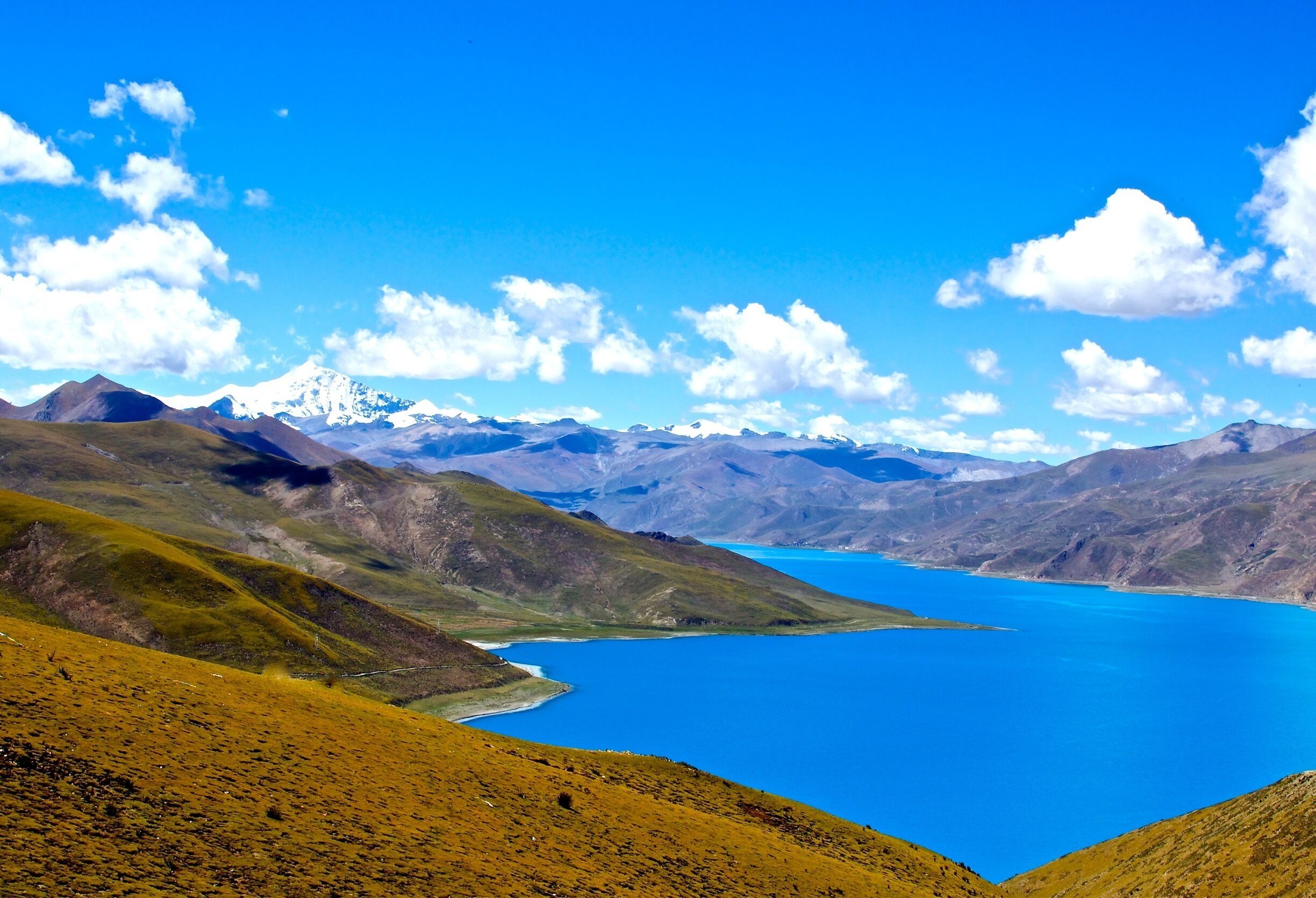 A mountainous landscape with a large blue lake and snow-capped peaks in the distance.