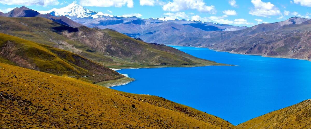 A mountainous landscape with a large blue lake and snow-capped peaks in the distance.