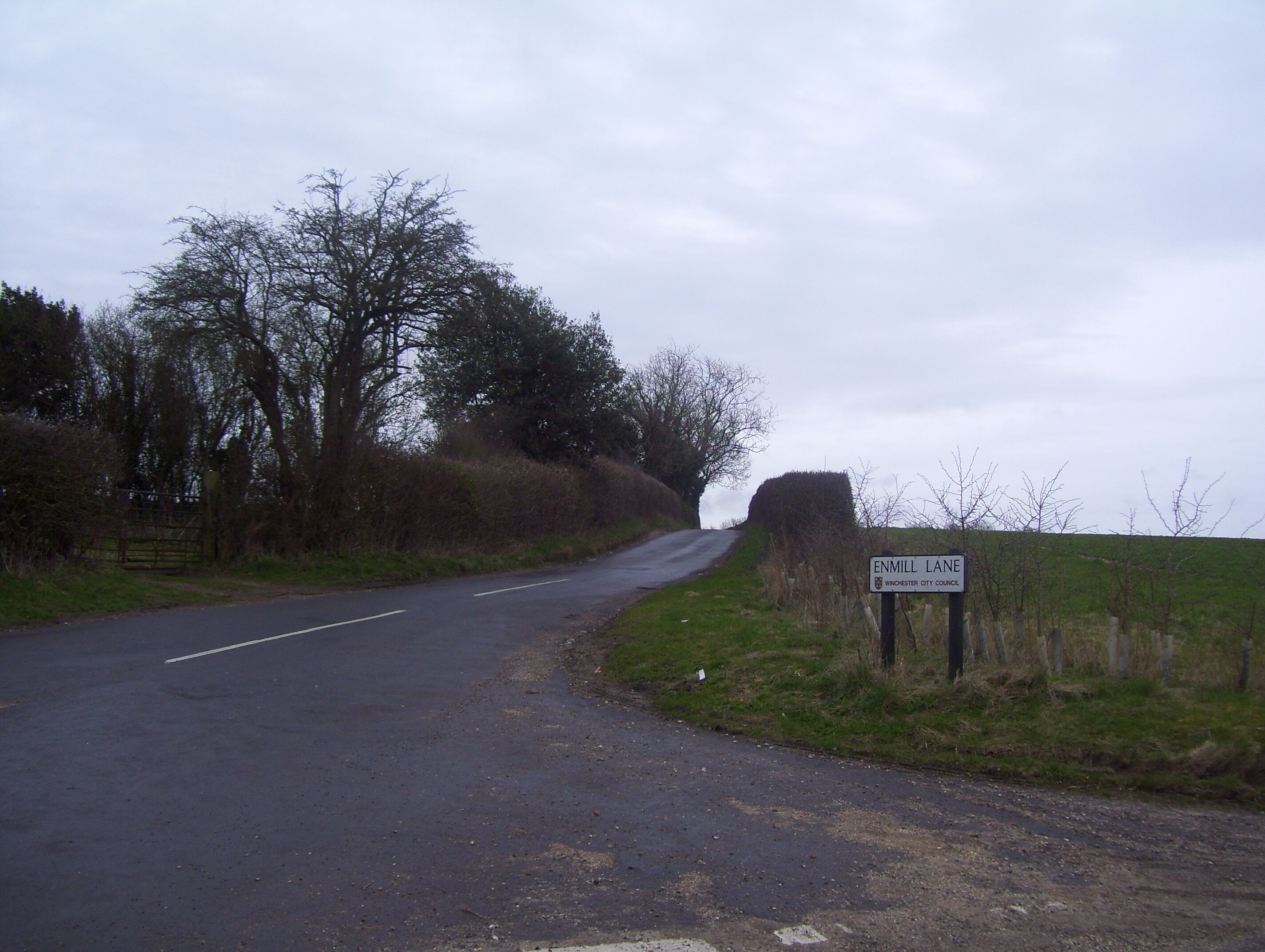 A rural road with a sign indicating Enmill Lane in Winchester City Council.